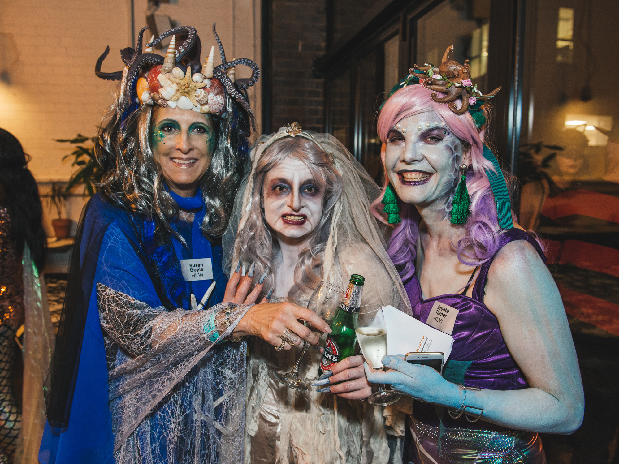 Three individuals in sea-themed costumes with elaborate headpieces, enjoying a costume event.