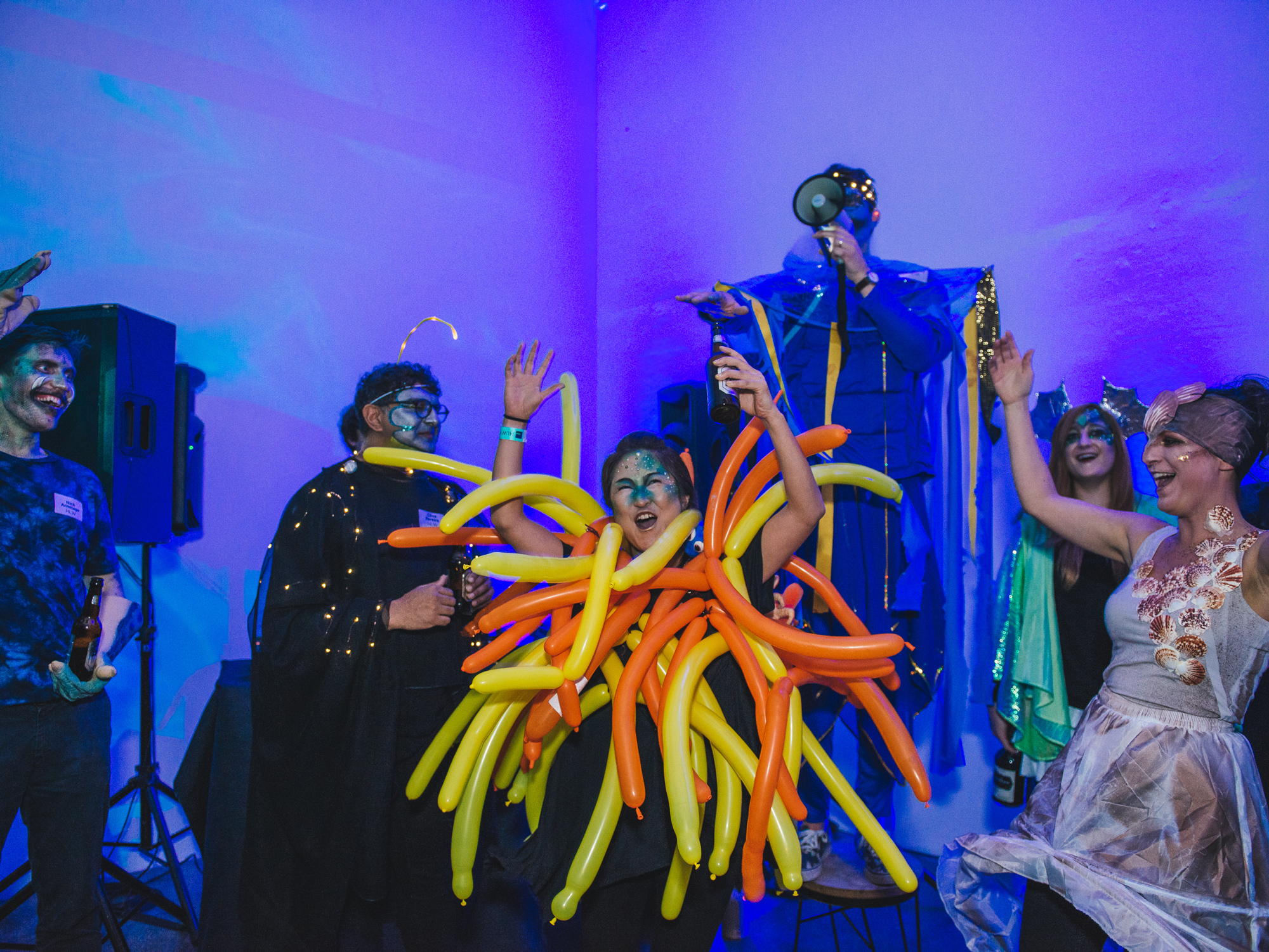 A group in whimsical attire with oversized balloon sculptures, creating a lively atmosphere at the event.