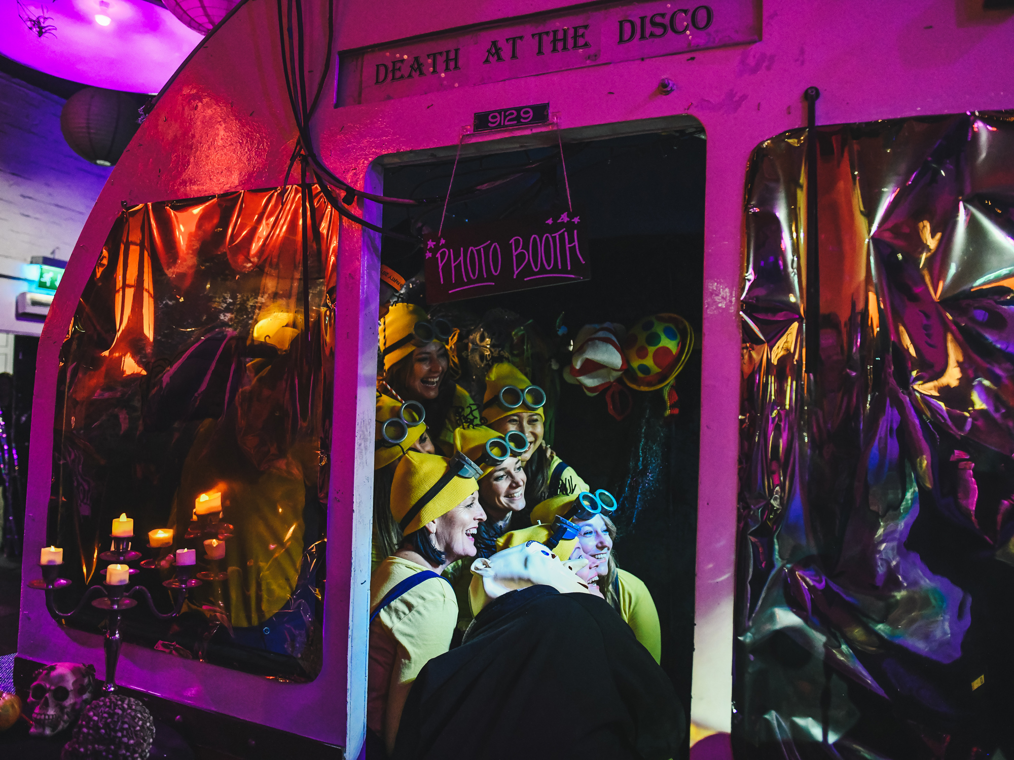 Joyful attendees in a photo booth at a themed event, “Death at the Disco,” enjoying the festive atmosphere.