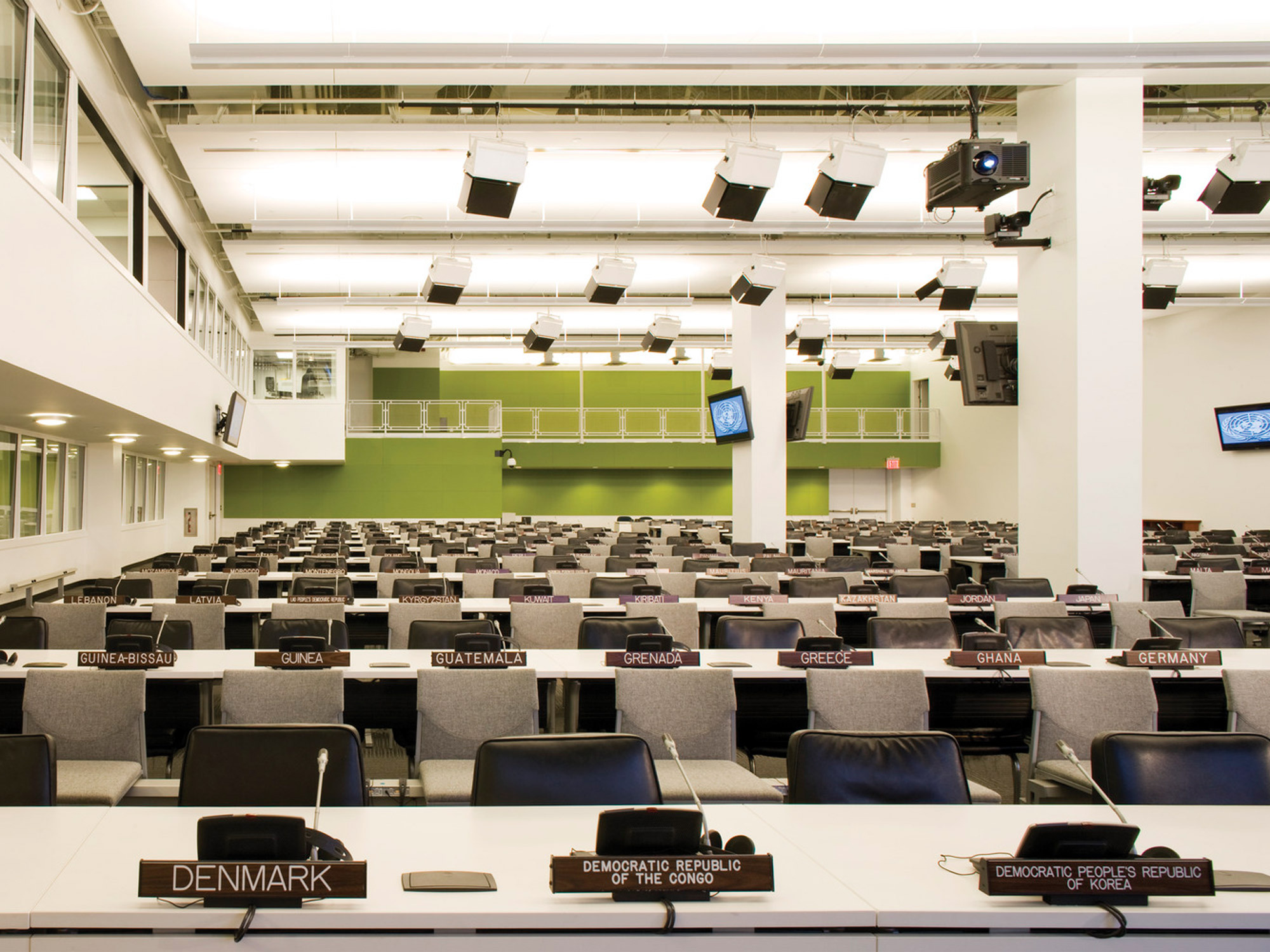 Modern lecture hall featuring tiered seating with individual workstations, built-in audiovisual equipment, and country nameplates in front of each row reflecting a model United Nations assembly hall.