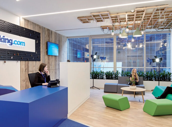 Bright, modern office reception area with a contemporary design featuring an illuminated logo on textured black wall, angular front desk, wood slat ceiling details, and vibrant green seating accents, fostering a dynamic and welcoming environment.