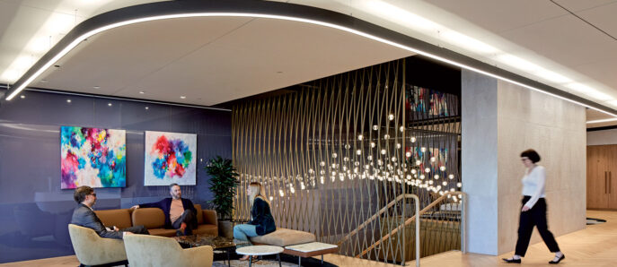 Modern office lobby featuring curved wooden slats, a cascade of spherical pendant lights, vibrant abstract artwork, and plush seating on geometric rugs over herringbone parquet flooring.