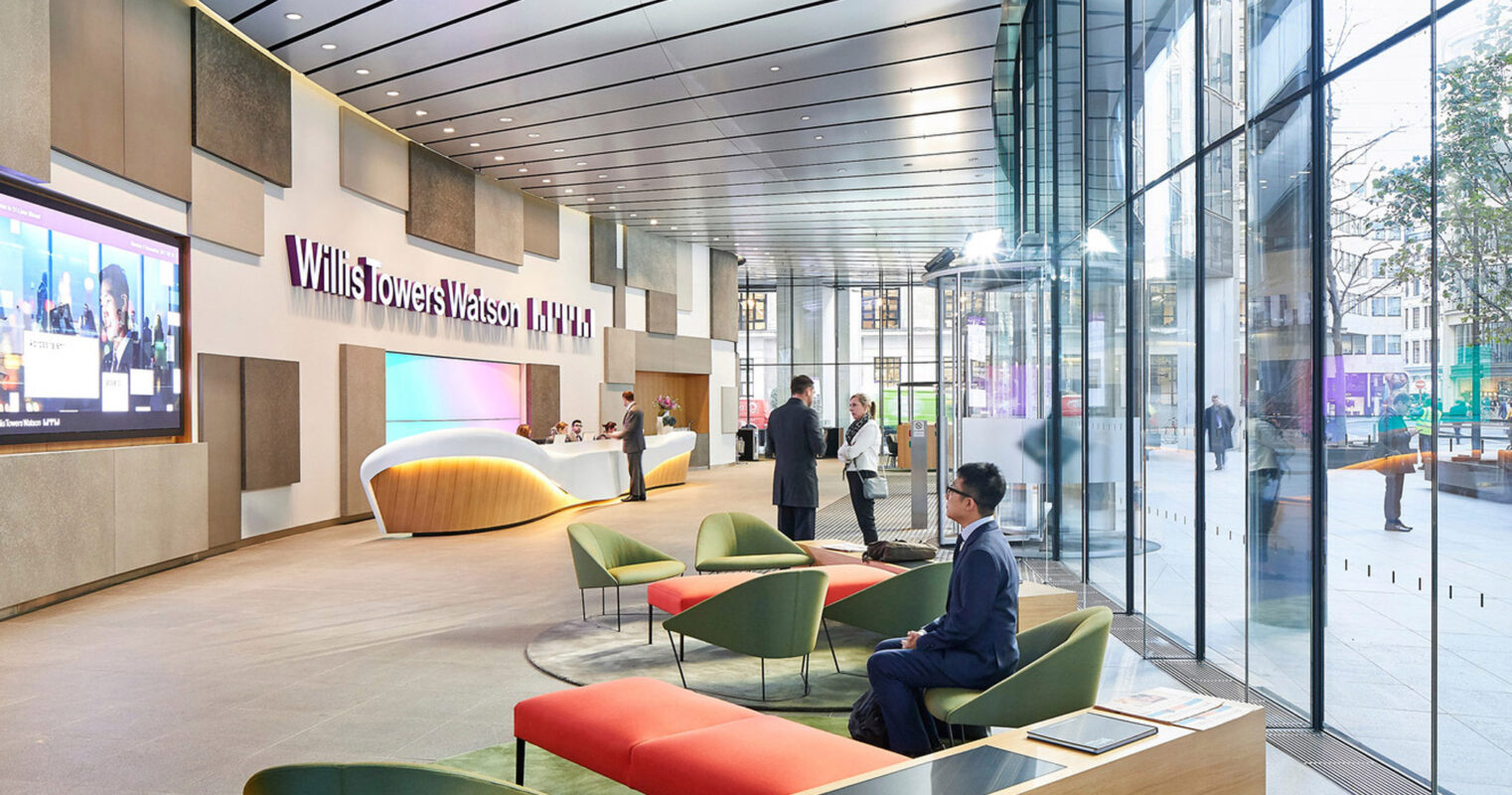 Modern corporate lobby featuring a curved reception desk, sleek glass walls, and an array of colorful seating options set on a polished concrete floor, accentuated by natural light and digital display screens.