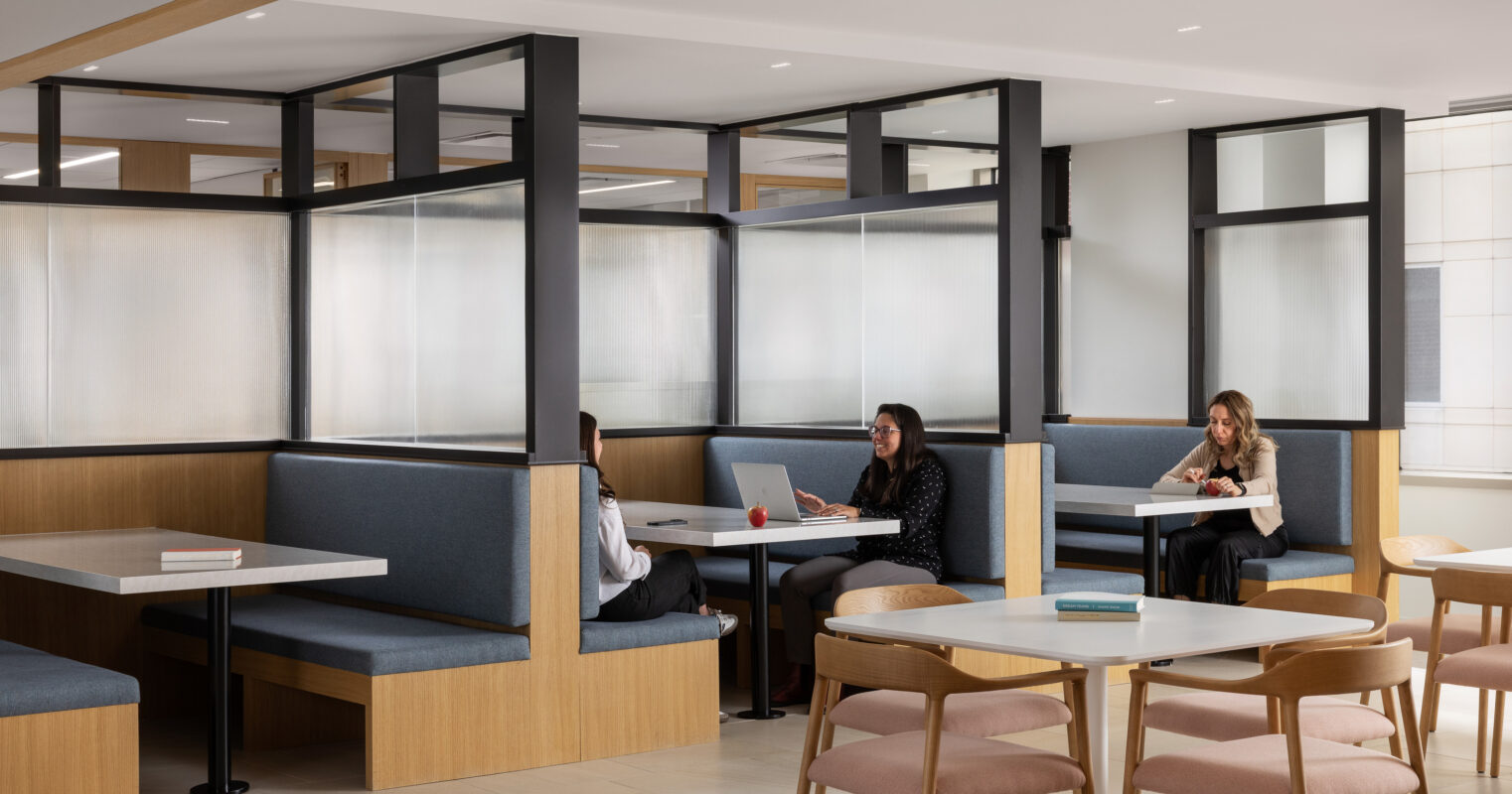 Modern coworking space featuring sleek, partitioned seating areas with a combination of soft blue upholstery and natural wood finishes. Bright, diffused lighting enhances the open atmosphere, while strategically placed tables promote collaboration. The design blends functionality with comfort, ideal for both individual work and group discussions.