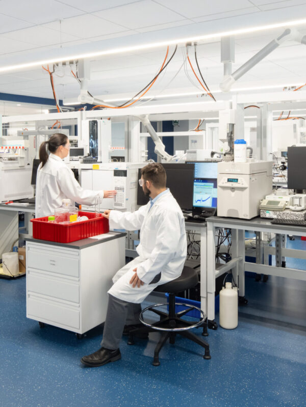 Modern laboratory environment featuring sleek, modular workstations equipped with advanced scientific equipment. The spacious layout promotes efficiency and collaboration among staff members, dressed in lab coats, as they engage in research activities. Bright lighting highlights the clean lines and functionality of the design, enhancing productivity in a professional setting.