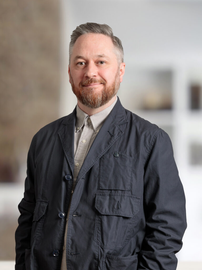 The image depicts a person dressed in casual attire, standing indoors.