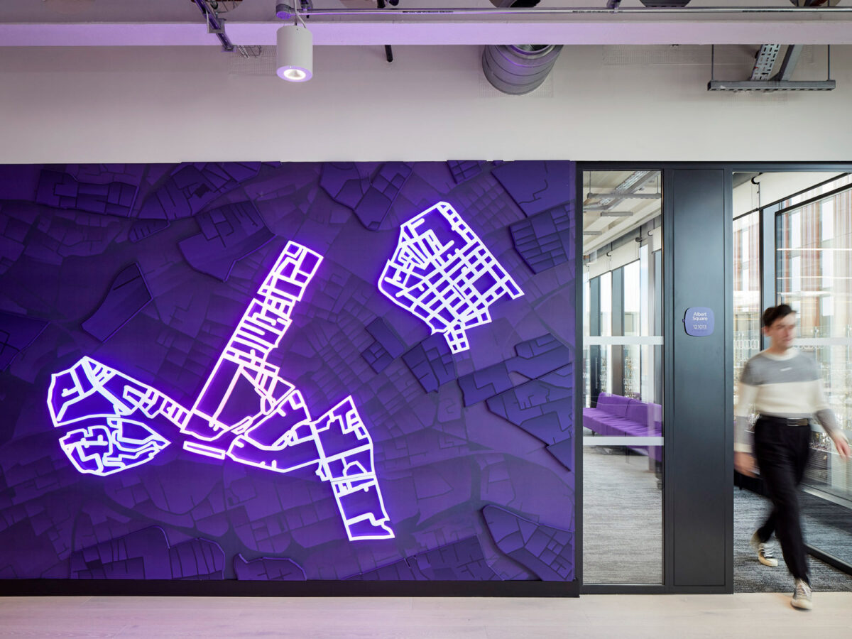 Modern office space featuring an avant-garde wall mural in electric purple, illustrating abstract geometric shapes. The design adds a vibrant, energetic touch to the professional setting, complemented by sleek glass doors and minimalistic furnishings.
