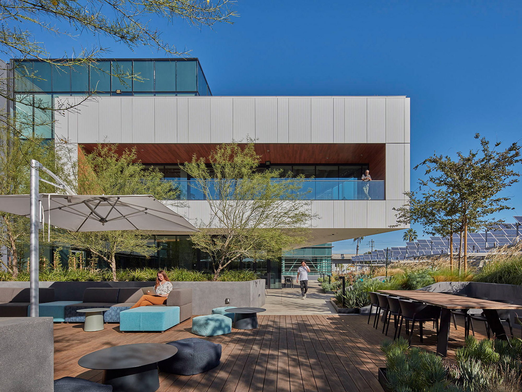 Modern architecture featuring a cantilevered building with clean white facades, expansive glass windows, and an integrated outdoor seating area with contemporary landscaping and hardscaping elements.
