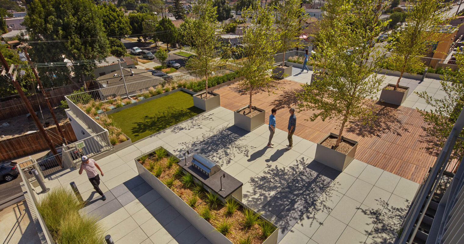 Rooftop terrace features modular seating and lush plantings, optimizing urban space with a green area and walkways, amidst a backdrop of cityscape and palm trees.