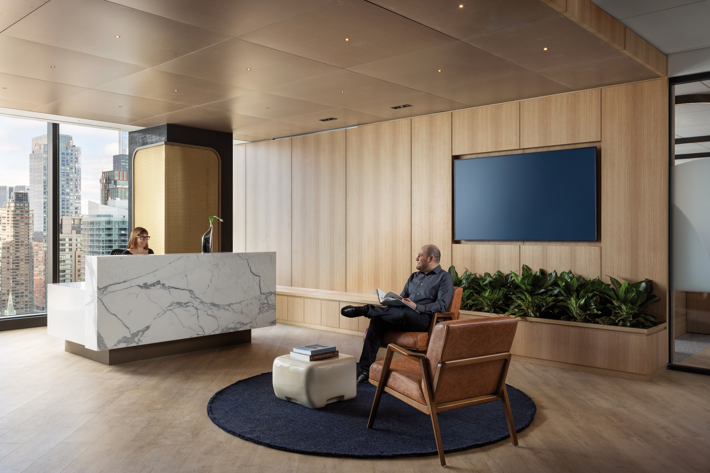 Minimalist office lobby featuring a sleek white marble reception desk, warm wooden wall panels, and a cozy seating area with a leather armchair, complemented by natural greenery and expansive city views through floor-to-ceiling windows.