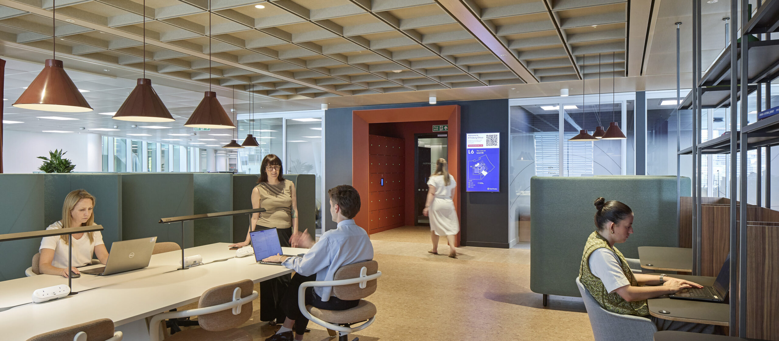 A modern open-plan office featuring collaborative workspaces and individual desks. Stylish mid-century furniture complements the innovative design, with pendant lighting enhancing the warm atmosphere. Natural light floods in through large windows, promoting productivity and creativity among engaged professionals, reflecting a contemporary approach to workplace design.