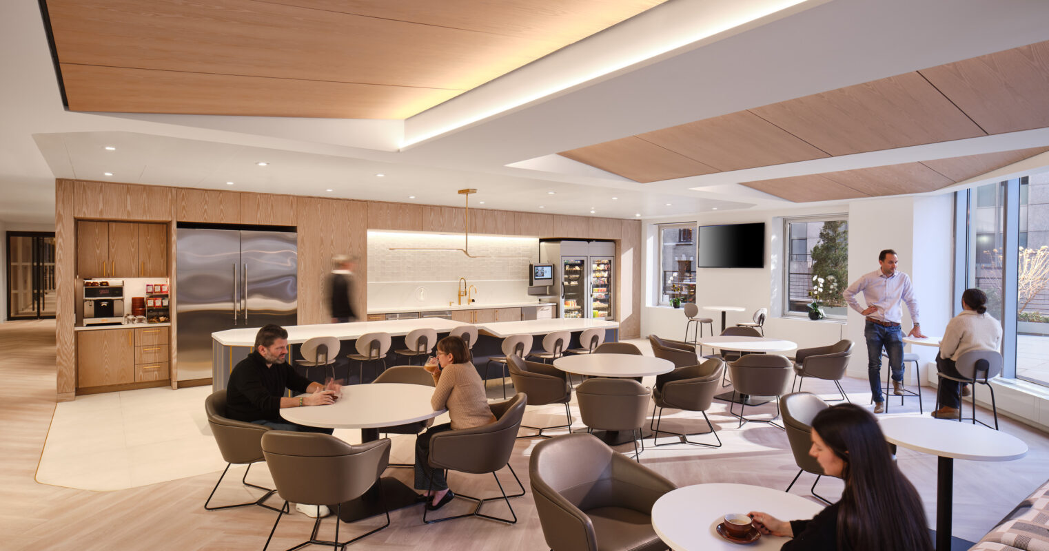 Contemporary break room featuring a spacious layout with seamless wood-paneled ceilings and soft, ambient lighting. Modern furniture, including round tables and plush chairs, encourages collaboration. Large windows fill the space with natural light, while sleek kitchen amenities provide convenience, promoting a welcoming and functional atmosphere for relaxation and social interaction.